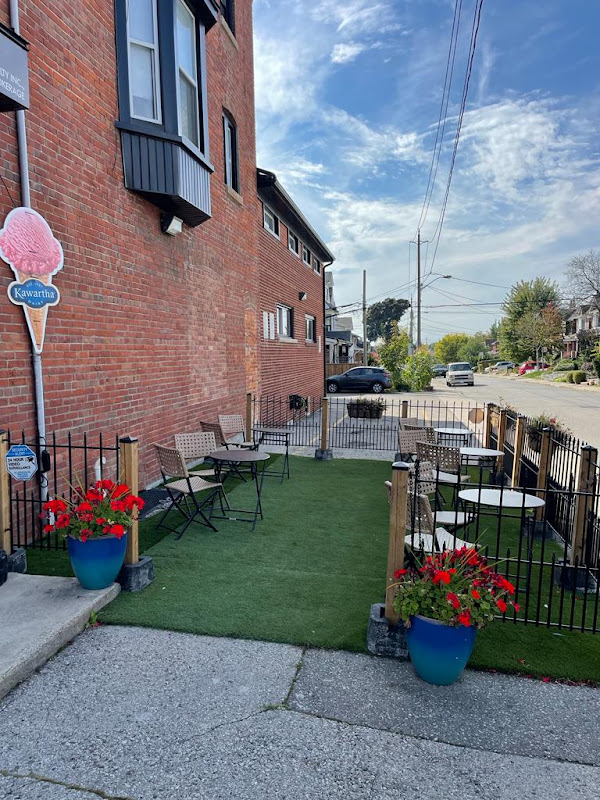 Kafe Dáki's outdoor tables and blue planters beside Oakwood Avenue